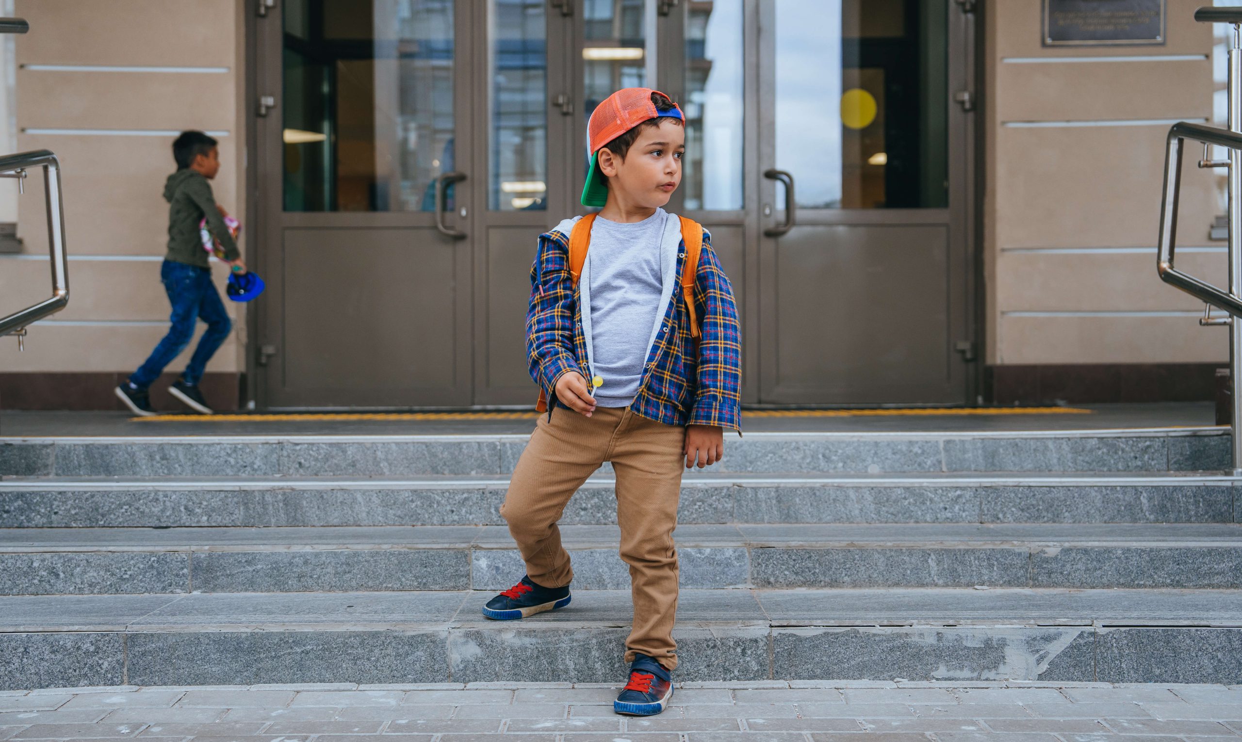 little boy in clean, stylish kids clothing standing outside on a staircase