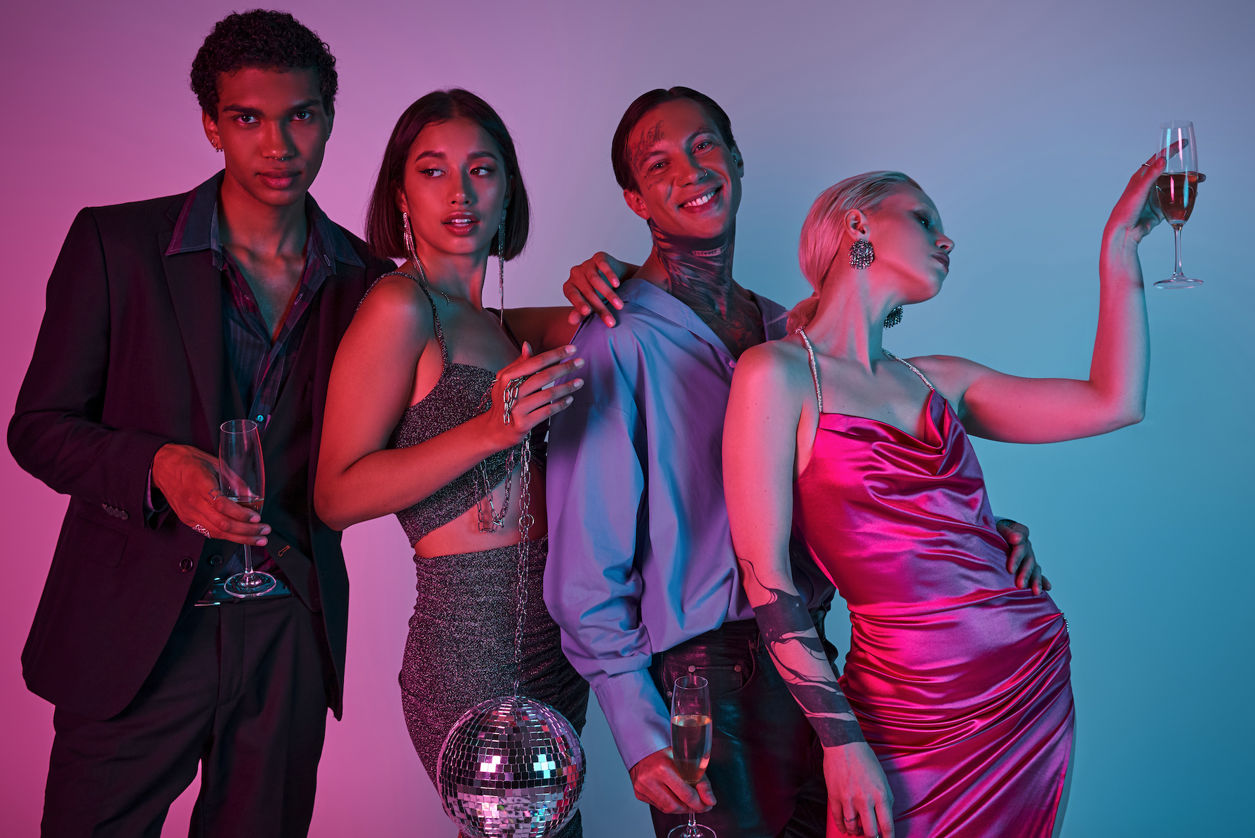 Group of stylish young people at a party, posing with champagne glasses, highlighted by colorful lighting.